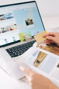 Person booking travel online with credit card and laptop