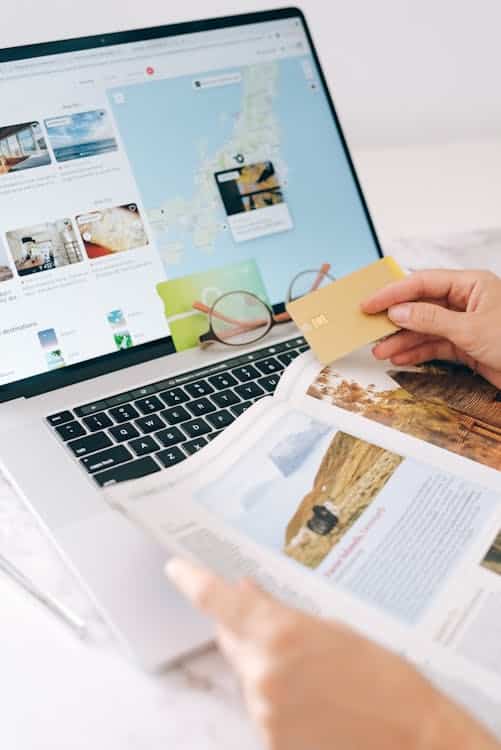 Person booking travel online with credit card and laptop